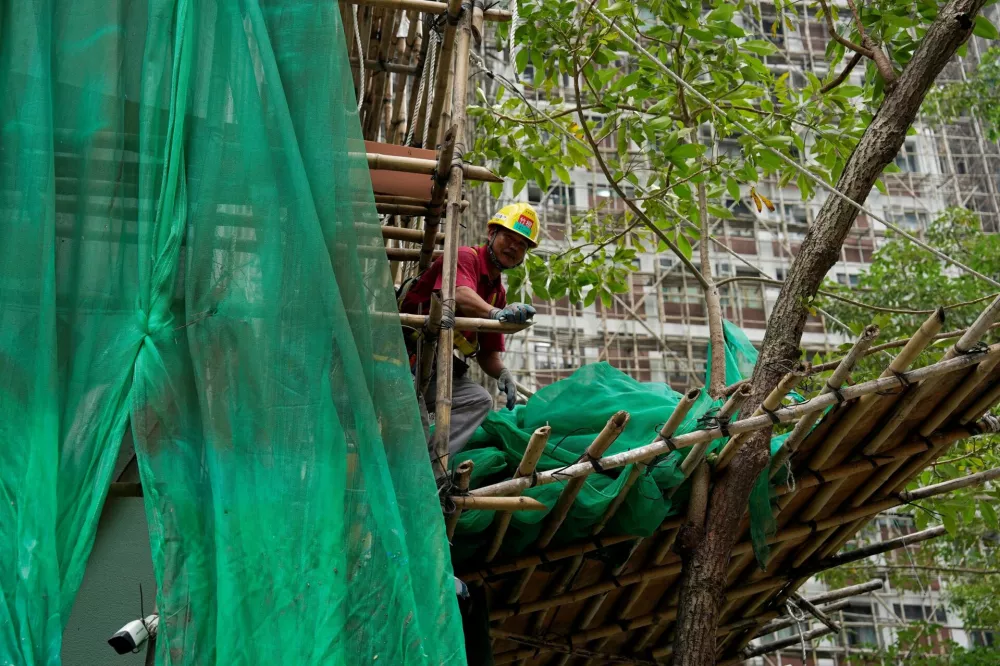 A worker removes scaffolding mesh from a building at Sui Wo Court in Sha Tin, following authorities' decision to remove the netting amid investigations into a deadly fire at Wang Fuk Court, in Hong Kong, China December 4, 2025. REUTERS/Vernon Yuen