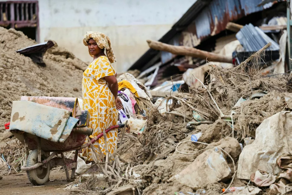 A woman stands as she waits for a ride while collecting valuable goods from her heavily damaged house, following deadly flash flood in Batang Toru, South Tapanuli, North Sumatra province, Indonesia, December 6, 2025. REUTERS/Willy Kurniawan