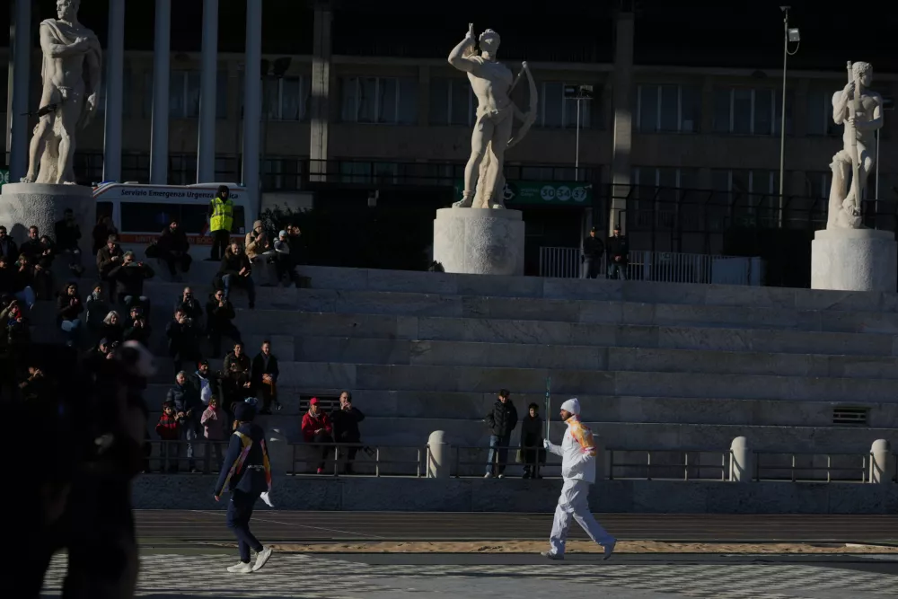 Italian swimmer Gregorio Paltrinieri carries the 2026 Milan Cortina Winter Olympics torch in Rome as it begins its journey through Italy, Saturday, Dec. 6, 2025, a journey that will conclude in Milan in February 2026. (AP Photo/Andrew Medichini)