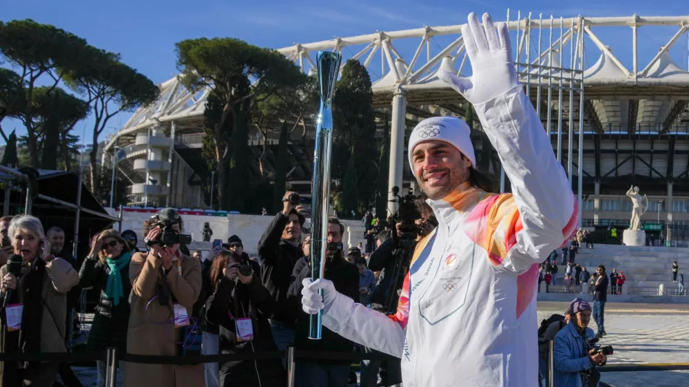 Italian swimmer Gregorio Paltrinieri carries the 2026 Milan Cortina Winter Olympics torch in Rome as it begins its journey through Italy, Saturday, Dec. 6, 2025, a journey that will conclude in Milan in February 2026. (AP Photo/Andrew Medichini)