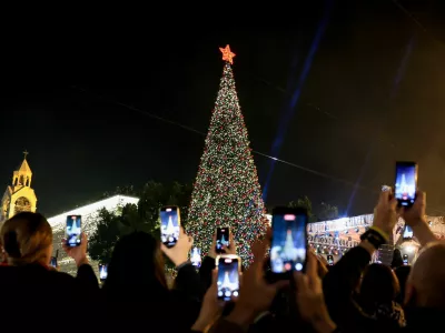 Palestinians use phones to record as a Christmas tree is lit up in Manger Square outside the Church of the Nativity, in Bethlehem, in the Israeli-occupied West Bank, December 6, 2025. REUTERS/Mussa Qawasma