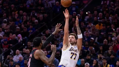 Los Angeles Lakers' Luka Doncic, right, shoots the ball against Philadelphia 76ers' Paul George, left, during the first half of an NBA basketball game, Sunday, Dec. 7, 2025, in Philadelphia. (AP Photo/Chris Szagola)