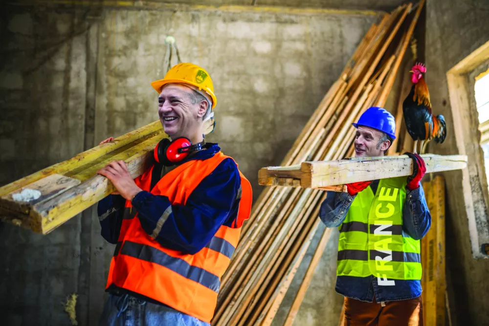 Two construction workers carrying a scaffolding at a building site - people at work concepts / Foto: Jovanmandic