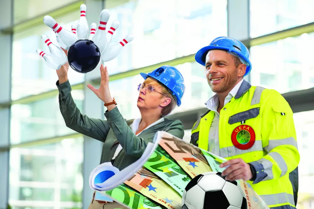 Young woman architect explaining blueprint to supervisor wearing safety vest at construction site. Mid adult contractor holding blueprint and understanding manager vision at construction site. Smiling engineer with hardhat on head talking to contractor while standing in building in construction process. / Foto: Ridofranz