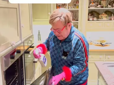 Sir Elton, znan po svojem ekscentričnem slogu oblačenja, je za či&scaron;čenje kuhinje oblekel modro trenerko, prekrito z logotipom znamke in mačjim motivom, v&scaron;itim na sprednji strani. F IG/posnetek zaslona 