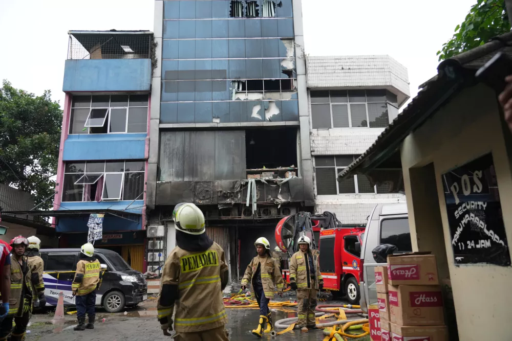 Rescuers work around an office building that caught fire in Jakarta, Indonesia, Tuesday, Dec. 9, 2025. (AP Photo/Dita Alangkara)