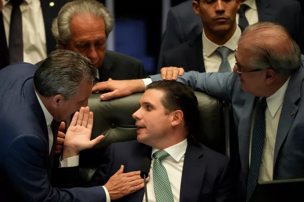 President of the Chamber of Deputies Hugo Motta, center, speaks with congressmen at a session to consider a bill to alter sentencing guidelines for certain crimes including leading a coup d'état, for which former President Jair Bolsonaro was sentenced, in Brasilia, Brazil, Tuesday, Dec. 9, 2025. (AP Photo/Eraldo Peres)