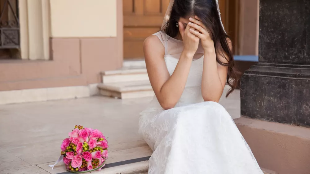 Hopeless bride crying outside a church after being stood up on her wedding day