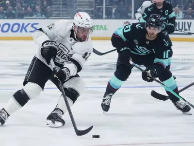 Los Angeles Kings center Anze Kopitar (11) pushes past Seattle Kraken center Matty Beniers (10) during the first period of an NHL hockey game Wednesday, Dec. 10, 2025, in Seattle. (AP Photo/Lindsey Wasson)