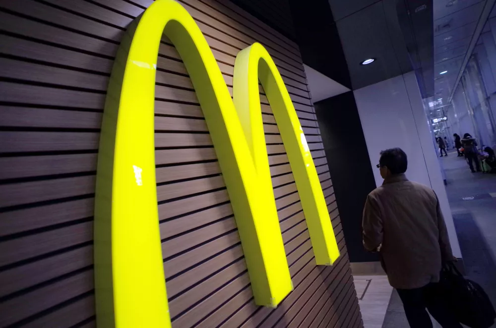 ﻿FILE - In this Dec. 17, 2014 file photo, a man walks by a McDonald's logo in front of its restaurant in Tokyo. McDonald's is set to unveil its latest plans to revive its sputtering business on Monday, May 4, 2015. (AP Photo/Eugene Hoshiko, File)