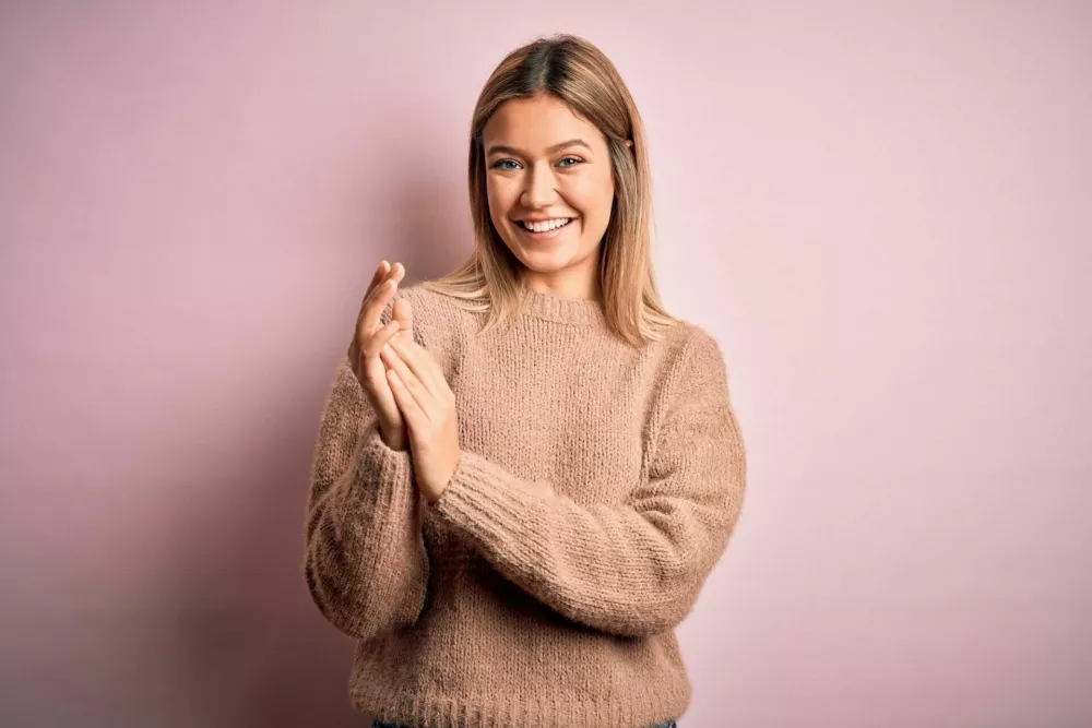 Young beautiful blonde woman wearing winter wool sweater over pink isolated background clapping and applauding happy and joyful, smiling proud hands together / Foto: Aaronamat