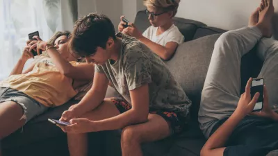 Group of teenager using smartphone sitting on a sofa at home. Young boys and a girl sharing photo and video watching social story online. Friends enjoying new trend technology. Youth and tech concept / Foto: Fabio Principe