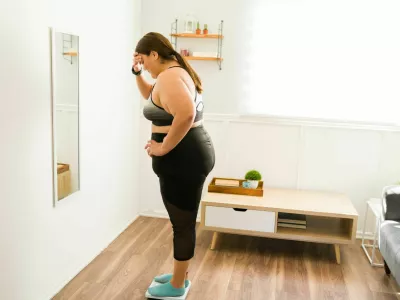 This is not healthy. Worried and sad fat woman using the scale and weighing herself / Foto: Antonio_diaz