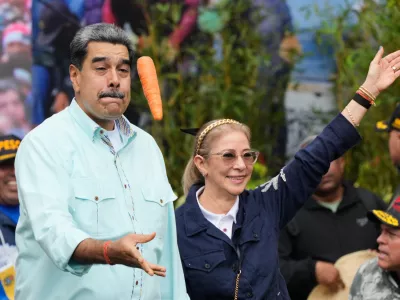 President Nicolas Maduro tosses a carrot next to his wife Cilia Flores during a rally marking the anniversary of the Battle of Santa Ines, which took place during Venezuela's 19th-century Federal War, in Caracas, Venezuela, Wednesday, Dec. 10, 2025. (AP Photo/Ariana Cubillos)