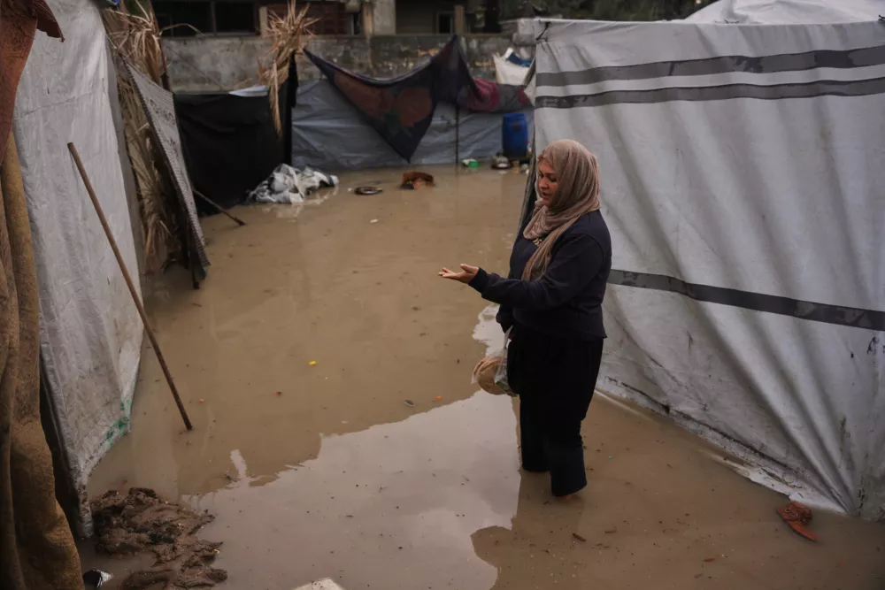 Lamia Abdel Dayem, 30, stands at her family's flooded tent in a temporary camp for displaced Palestinians, after heavy rainfall in Deir al-Balah, central Gaza Strip, Friday, Dec. 12, 2025. (AP Photo/Abdel Kareem Hana)
