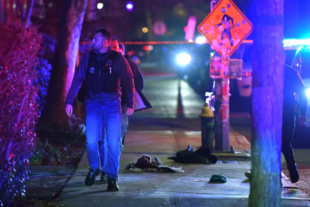 A law enforcement official walks past articles of clothing on a sidewalk near an entrance to Brown University, Saturday, Dec. 13, 2025, in Providence, R.I., during the investigation of a shooting. (AP Photo/Steven Senne)