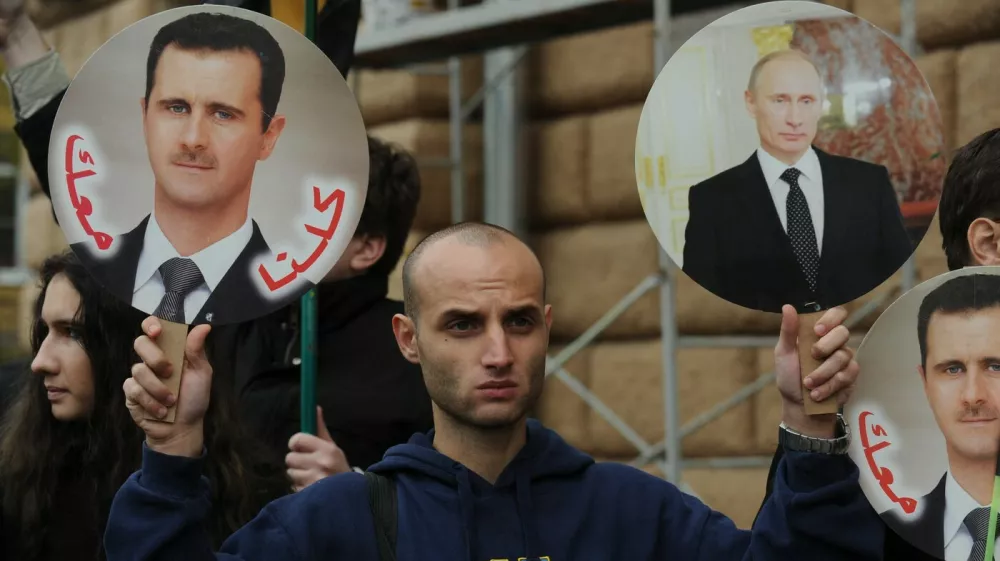 A man holds portrait of Russia's President Vladimir Putin (R) and Syria's President Bashar al-Assad (L) during a rally in support of Syrian regime in front of the US Embassy in Moscow, on October 19, 2012. Moscow has defiantly refused to take sides against Assad, and has slammed the West and Turkey for making clear their support for the rebels battling his regime.,Image: 144327568, License: Rights-managed, Restrictions:, Model Release: no