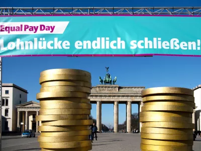 FILED - 07 March 2022, Berlin: Figures of coins pile up under a banner at an Equal Pay Day event in front of the Brandenburg Gate. Photo: Paul Zinken/dpa