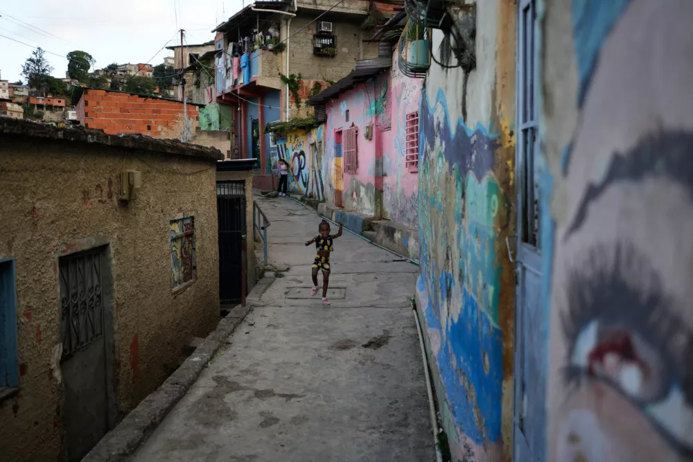 A girl walks in alley in the neighborhood of San Agustin in Caracas, Venezuela, Friday, Dec 19, 2025. (AP Photo/Ariana Cubillos)