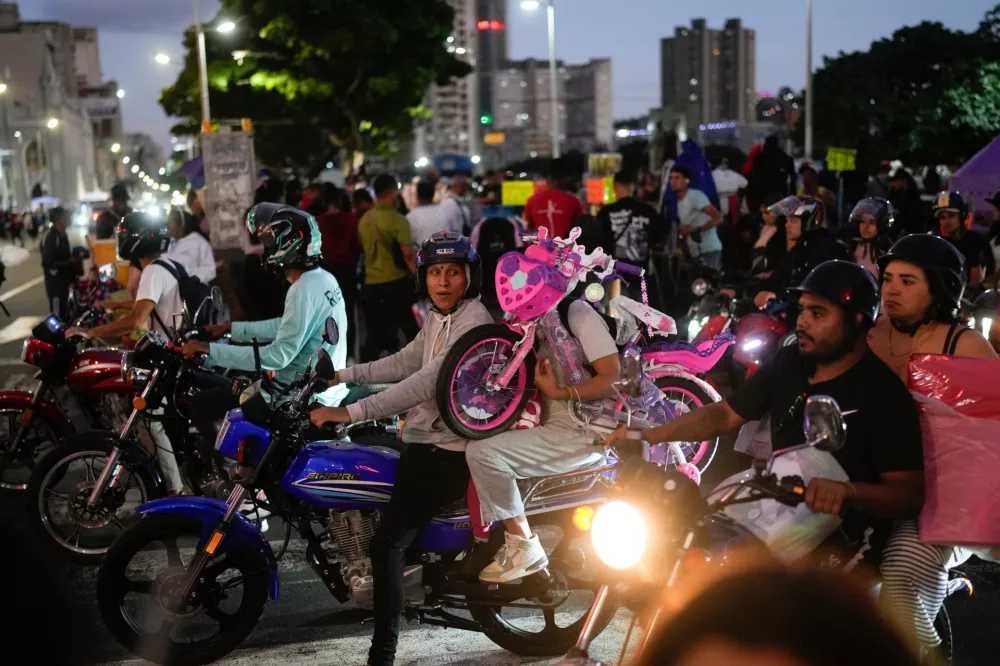 A woman carries a bicycle on a motorbike during the weekend leading up to Christmas in downtown Caracas, Venezuela, Saturday, Dec. 20, 2025. (AP Photo/Matias Delacroix)