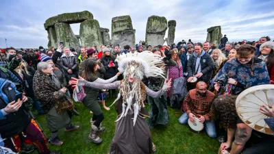 Kefan Wang, a shaman from China and Abbie Coombs from London dancing as people celebrate the Winter Solstice sunrise celebrations at Stonehenge, a world-famous prehistoric monument on Salisbury Plain, England, Sunday, Dec. 21, 2025. (AP Photo/Anthony Upton)