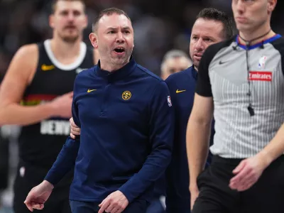 Denver Nuggets head coach David Adelman, front left, reacts after being ejected by referee Tyler Ricks, right, as assistant coach J.J. Barea, second from right, holds him back in the second half of an NBA basketball game against the Houston Rockets, Saturday, Dec. 20, 2025, in Denver. (AP Photo/David Zalubowski)