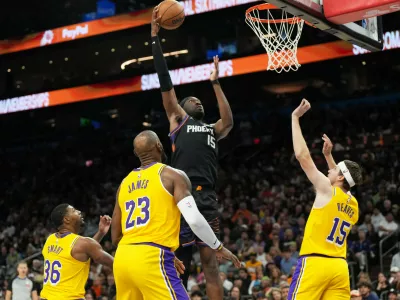 Phoenix Suns center Mark Williams scores between Los Angeles Lakers guard Marcus Smart (36), forward Lebron James (23), and guard Austin Reaves during the second half of an NBA basketball game, Tuesday, Dec. 23, 2025, in Phoenix. (AP Photo/Rick Scuteri)
