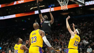 Phoenix Suns center Mark Williams scores between Los Angeles Lakers guard Marcus Smart (36), forward Lebron James (23), and guard Austin Reaves during the second half of an NBA basketball game, Tuesday, Dec. 23, 2025, in Phoenix. (AP Photo/Rick Scuteri)