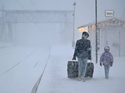 People walk under heavy snow as departures are cancelled at the train station in Are, Sweden, Saturday Dec. 27, 2025. (Pontus Lundahl/TT News Agency via AP)