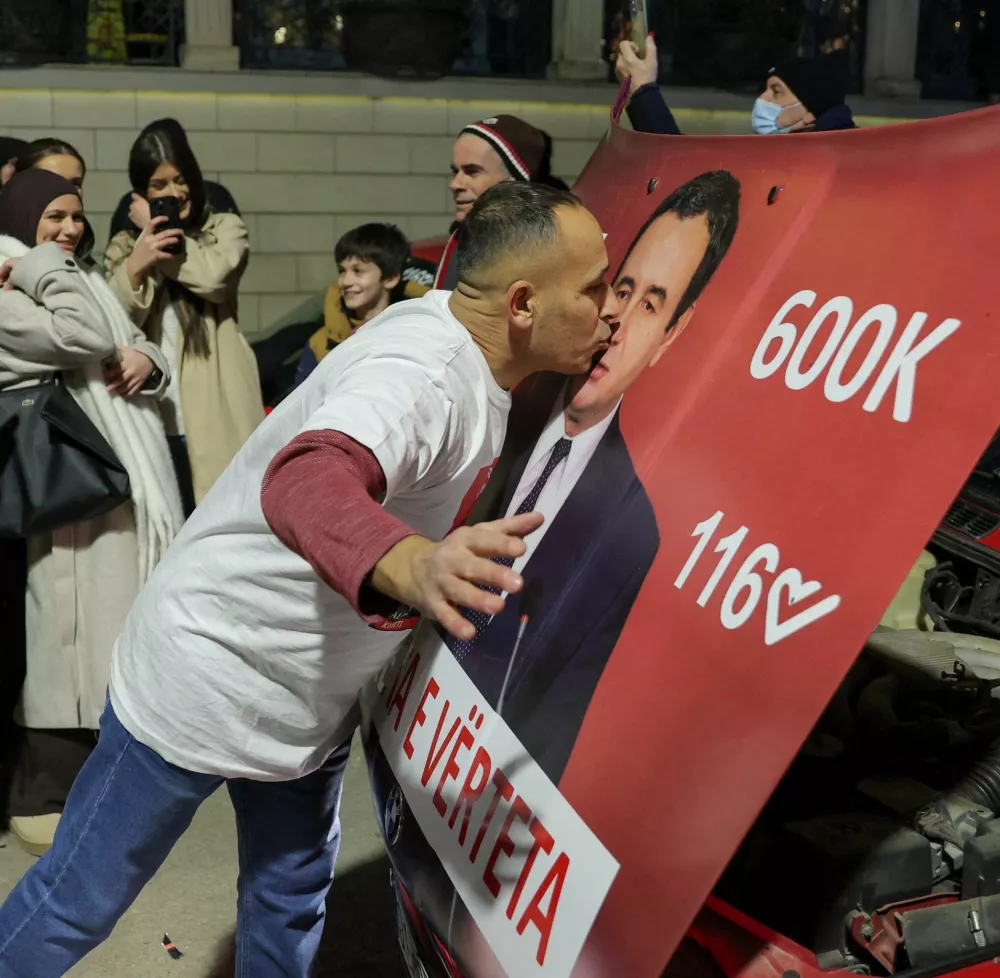 A man kisses a hood of a car with an image of Kosovo's Prime Minister and Levizja Vetevendosje (Movement for Self-Determination) party leader Albin Kurti, as the party leads in early vote results, on the day of a snap parliamentary election, nearly a year after a political deadlock that prevented the formation of a new government, in Pristina, Kosovo, December 28, 2025. REUTERS/Valdrin Xhemaj REFILE - CORRECTING INFORMATION FROM "KISSES A POSTER" TO "KISSES A HOOD OF A CAR".