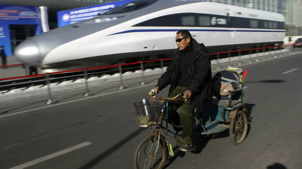 A resident rides a tricycle past the head of a CRH (China Railway High-speed) Harmony bullet train outside an exhibition for the Seventh World Congress on High Speed Rail in Beijing December 7, 2010. China plans to build 13,000 km (8,078 miles) of high-speed railway by 2012, more than the rest of the world combined. REUTERS/Jason Lee (CHINA - Tags: BUSINESS POLITICS TRANSPORT SOCIETY)