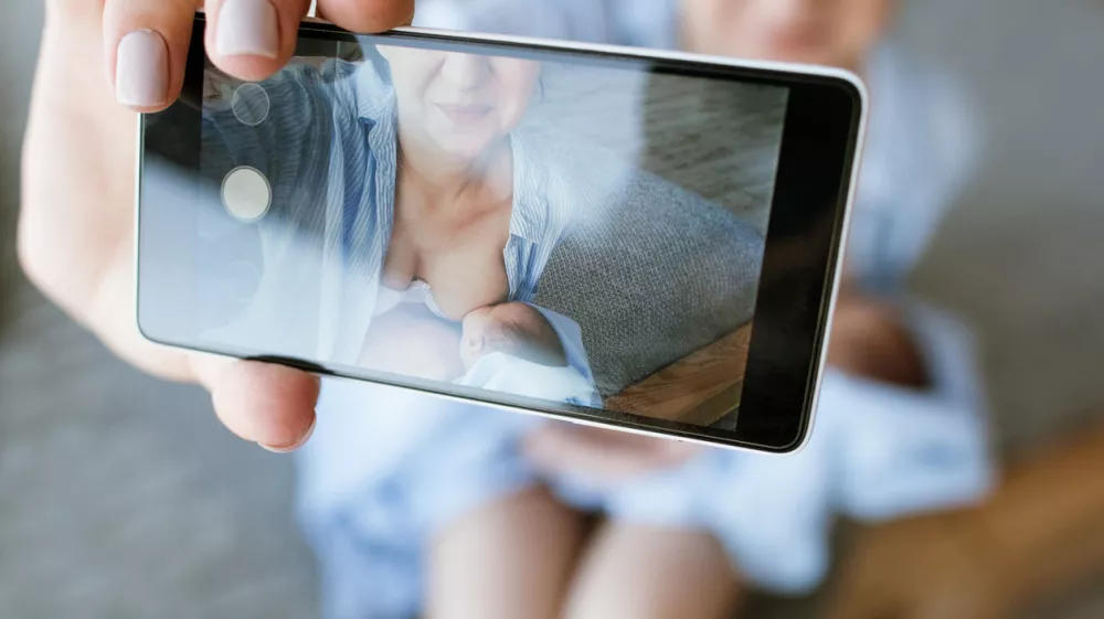 mother breastfeeding mobile photo newborn baby concept. family memories selfie.