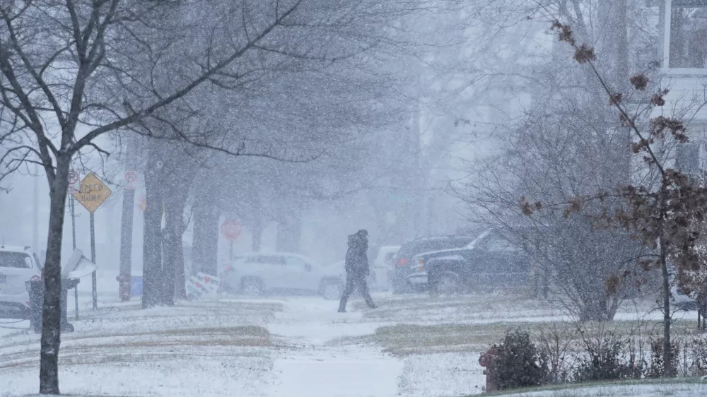 A person walks across the street after a winter storm system hit South East Michigan, Monday, Dec. 29, 2025, in Detroit. (AP Photo/Ryan Sun)
