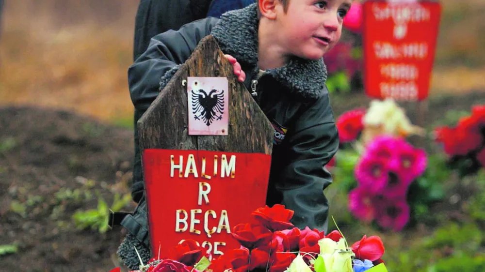 During a ceremony to mark the religious holiday of Eid al-Fitr, Kosovo Albanian boys stand by the grave of a relative killed by Serbian forces in January 1999 in the village of Racak, some 30 kilometres (20 miles) south of the Kosovo capital Pristina, November 4, 2005. Muslims all over the world celebrate Eid al-Fitr at the end of the holy month of Ramadan. REUTERS/Hazir Reka------3kol