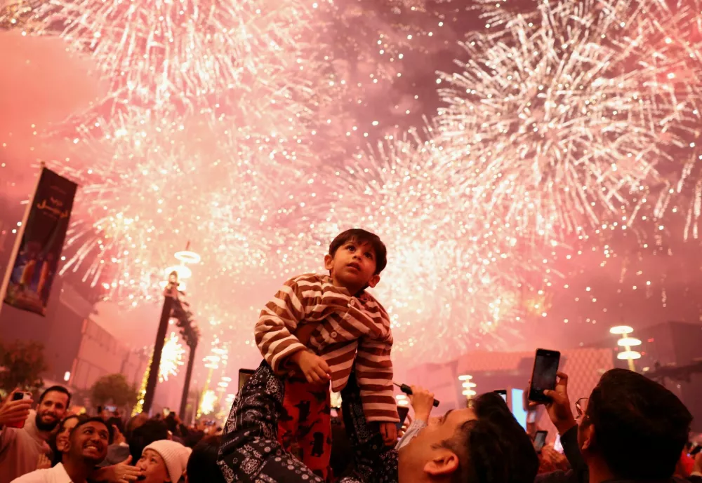 A child looks up as fireworks explode during New Year's celebrations in Lusail, Qatar, January 1, 2026. REUTERS/Mohammed Salem   TPX IMAGES OF THE DAY