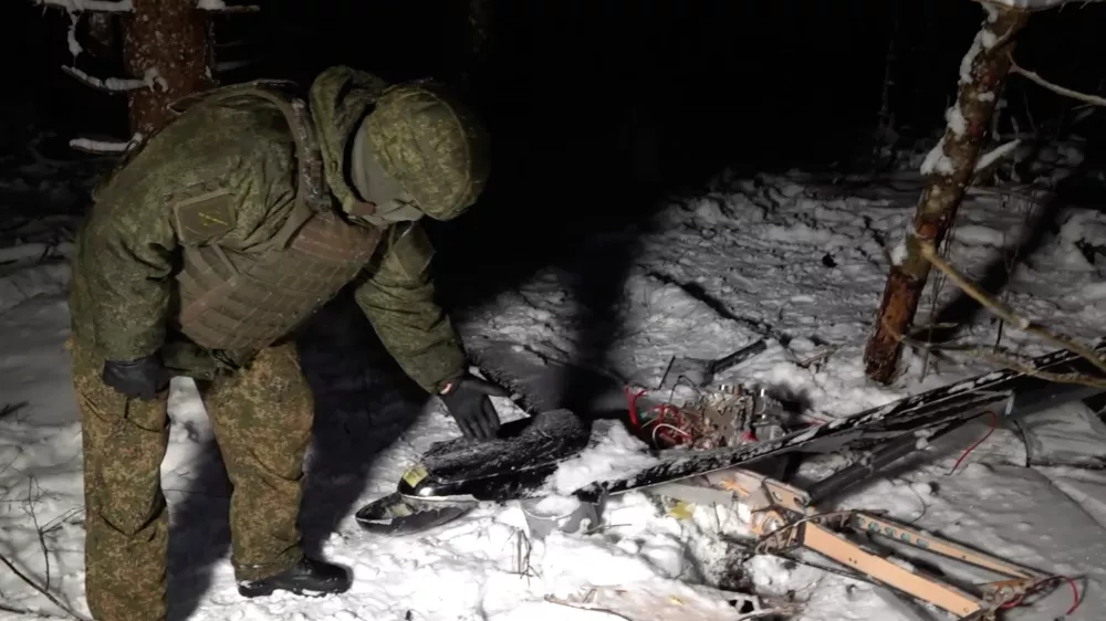 This image made from undated video provided by the Russian Defense Ministry Press Service on Wednesday, Dec. 31, 2025, shows a man in camouflage standing by a downed drone at an undisclosed location that it said was one of the Ukrainian drones involved in an alleged attack on a residence of President Vladimir Putin this week &ndash; a claim Kyiv has denied as a "lie". (Russian Defense Ministry Press Service via AP)
