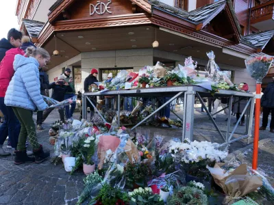 People bring flowers and letters near the sealed off Le Constellation bar, where a devastating fire left dead and injured during the New Year's celebrations in Crans-Montana, Swiss Alps, Switzerland, Friday, Jan. 2, 2026. (AP Photo/ Antonio Calanni)