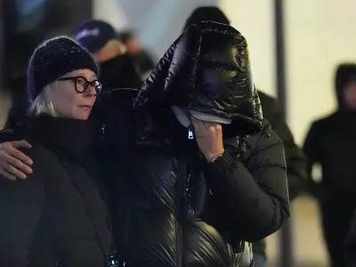 People mourn near the sealed off Le Constellation bar in Crans-Montana, Swiss Alps, Switzerland, Friday, Jan. 2, 2026, where a devastating fire left dead and injured during the New Year's celebrations. (AP Photo/ Antonio Calanni)