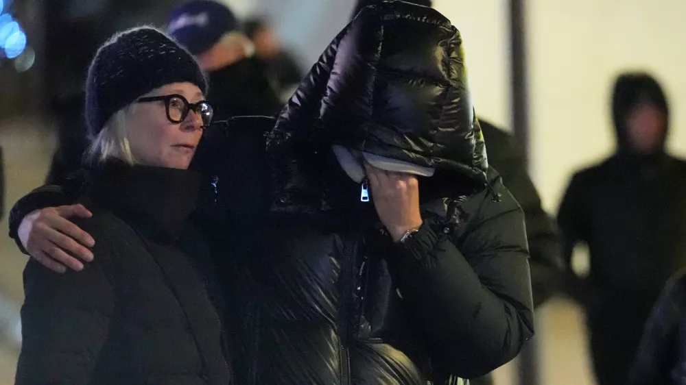 People mourn near the sealed off Le Constellation bar in Crans-Montana, Swiss Alps, Switzerland, Friday, Jan. 2, 2026, where a devastating fire left dead and injured during the New Year's celebrations. (AP Photo/ Antonio Calanni)