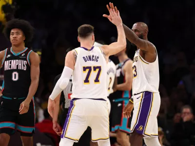 Jan 4, 2026; Los Angeles, California, USA; Los Angeles Lakers forward LeBron James (right) is greeted by forward Luka Doncic (77) after making a basket during the fourth quarter against the Memphis Grizzlies at Crypto.com Arena. Mandatory Credit: Kiyoshi Mio-Imagn Images