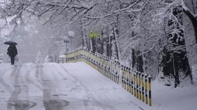 A woman walks through the snow covered street during a snowfall in Belgrade, Serbia, Sunday, Jan. 4, 2026. (AP Photo/Darko Vojinovic)