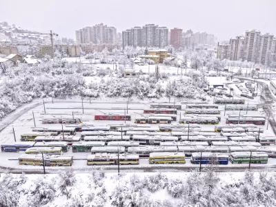 An aerial view of parked trolley buses during heavy snowfall in Sarajevo, Bosnia, Tuesday, Dec. 24, 2024. (AP Photo/Armin Durgut)