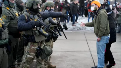 A federal agent gestures towards a demonstrator at a protest against the fatal shooting of Renee Nicole Good by a U.S. Immigration and Customs Enforcement (ICE) agent, during a rally against increased immigration enforcement across the city outside the Whipple Building in Minneapolis, Minnesota, U.S., January 8, 2026. REUTERS/Tim Evans