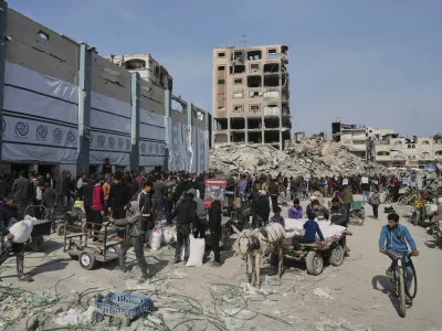 Palestinians receive bags of flour and other humanitarian aid distributed by UNRWA, the U.N. agency helping Palestinian refugees in Jabaliya, Gaza Strip on Tuesday, March 25, 2025. (AP Photo/Jehad Alshrafi)