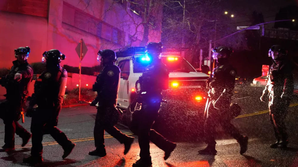 Portland police officers walk outside the U.S. Immigration and Customs Enforcement facility on Thursday, Jan. 8, 2026, in Portland, Ore. (AP Photo/Jenny Kane)