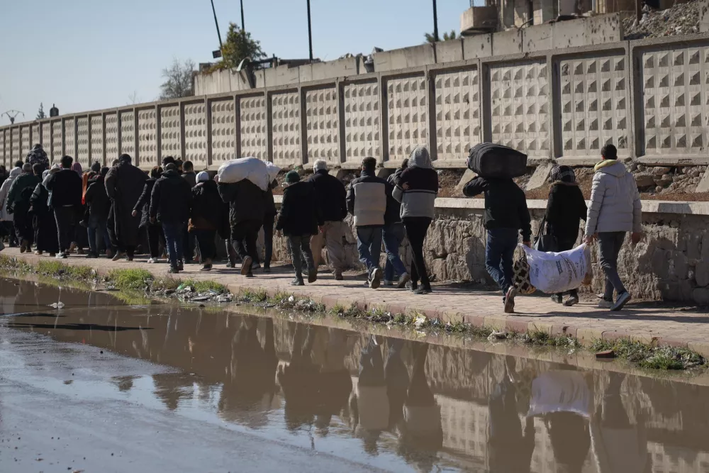 Civilians evacuate an area of the Sheikh Maqsoud neighborhood, where clashes between government forces and Kurdish fighters have been taking place in the northern city of Aleppo, Syria, Saturday, Jan. 10, 2026. (AP Photo/Omar Albam)