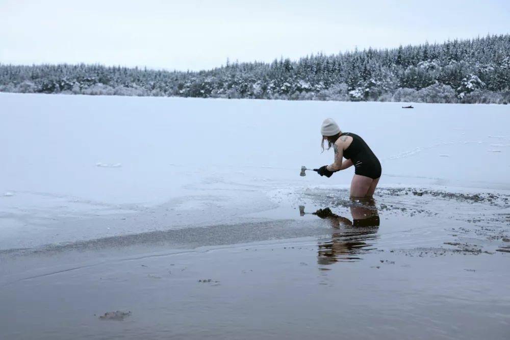 Ice swimmer Justina Pliuskeviciute uses an axe to break the ice on Loch Morlich, with Scotland in the grip of a deep freeze following Storm Goretti, near Aviemore, Scotland, Britain, January 9, 2026. REUTERS/Russell Cheyne
