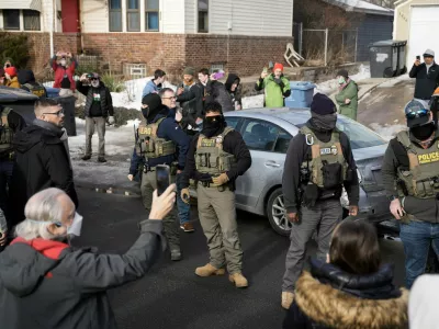 U.S. Immigration and Customs Enforcement (ICE) agents stand by a damaged civilian's car, which was hit by ICE, after an ICE agent fatally shot Renee Nicole Good, in Minneapolis, Minnesota, U.S., January 12, 2026.  REUTERS/Tim Evans