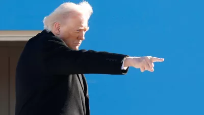 President Donald Trump gestures from the stairs of Air Force One as he boards upon his arrival at Joint Base Andrews, Md., Tuesday, Jan. 13, 2026. (AP Photo/Luis M. Alvarez)