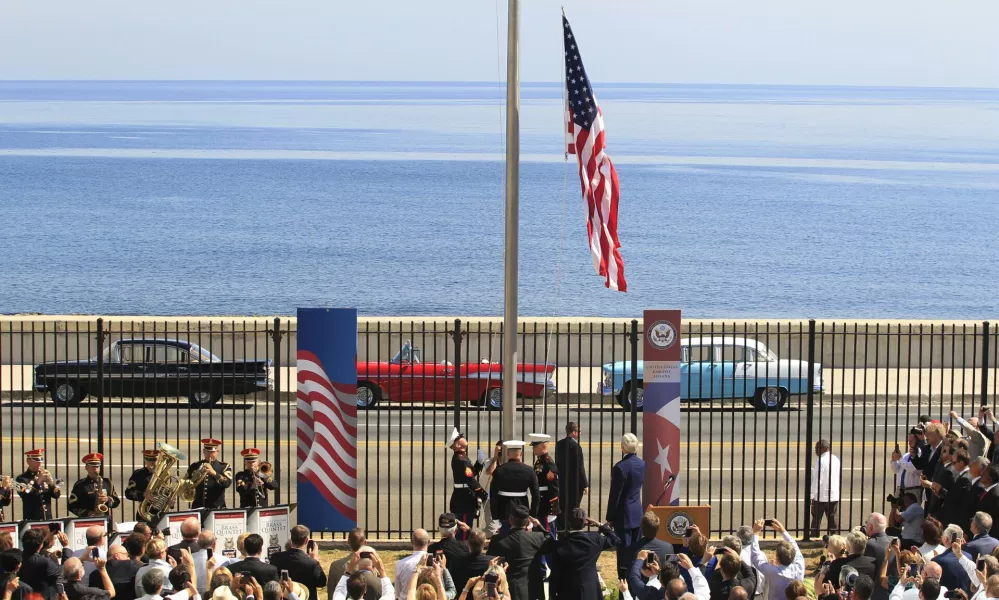 U.S. marines raise the U.S. flag while watched over by U.S. Secretary of State John Kerry (C, at lectern, back to camera) at the U.S. embassy in Havana, Cuba, August 14, 2015. U.S. Marines raised the American flag at the embassy in Cuba for the first time in 54 years on Friday, symbolically ushering in an era of renewed diplomatic relations between the two Cold War-era foes. REUTERS/Stringer    TPX IMAGES OF THE DAY